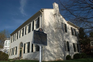 A photo of the Weeden House Museum with a historical marker. The house museum is a large white building with many windows