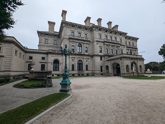 A large 3 story mansion rears up against a cloudy sky