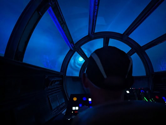 The back of a man's head at the helm of the Millennium Falcon as it goes into hyperspace