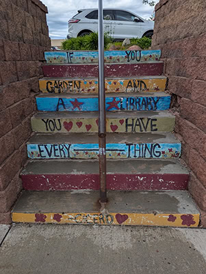 A colorful set of stairs with a quote  on the risers. The paint is a little damaged so all that can be read is "If you...garden and a library you have everything...Cicero"